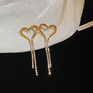 Macro detail of gold heart tassel earrings with sparkling cubic zirconia on soft fabric