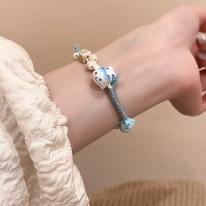 Detail of blue and white ceramic cat pendant on braided rope bracelet with wooden beads