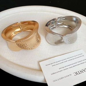 Irregular hammered metal oval hinge bracelet in polished gold and silver finishes