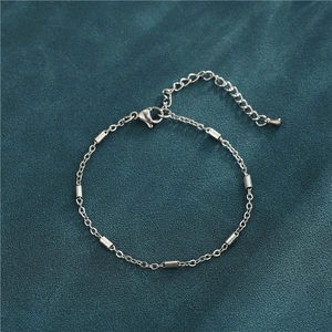 Macro detail of silver stainless steel cylinder bracelet on premium green velvet