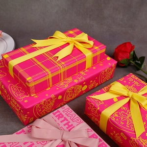 Papier cadeau d'anniversaire rose avec ruban en satin jaune et décor de roses