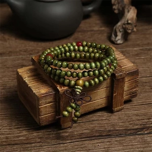 Detailed view of green sandalwood Buddhist beads with red accents on a vintage wooden box