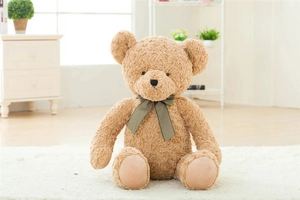 Close-up of curly brown teddy bear plush skin with a green striped bow on a white rug