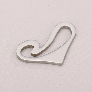Macro shot of silver asymmetrical heart-shaped stainless steel pendant on light fabric