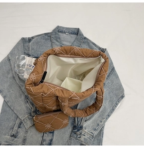 Interior detail of quilted brown tote bag showing white lining and small pouch