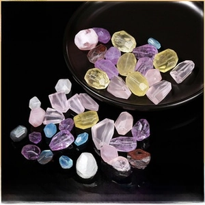 Close-up of multi-colored faceted natural crystal beads on a black tray