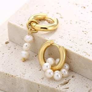 Detailed macro view of asymmetric gold-plated earrings with multiple white pearls