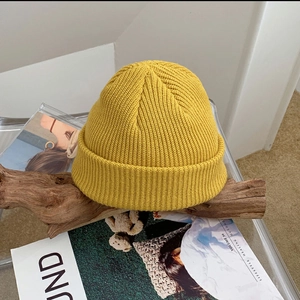 Winter chunky knit beanie in bright yellow shown on a decorative wooden background