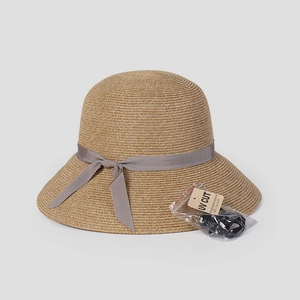 Detail of woven straw sun hat with ribbon bow and UV protection tag and wind cord