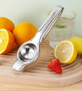 Macro shot of a stainless steel manual lemon squeezer on a wooden board in a kitchen setting