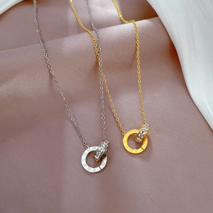 Detail of gold and silver interlocking double ring pendants with Roman numerals and zircons