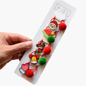 Detail of Christmas hair ties featuring Santa and reindeer charms on plush red bands