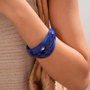 Detail of a dark blue marble resin bangle with a wide polished acrylic finish