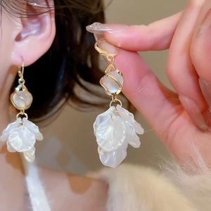 Close-up of petal-shaped tassel earrings with white pearls and gold metal frames