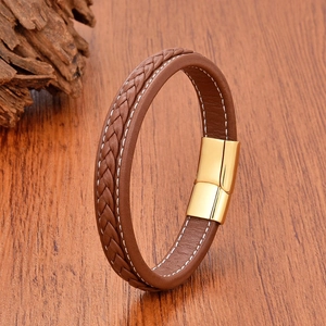 Close-up of brown braided leather bracelet with golden magnetic clasp on wood background
