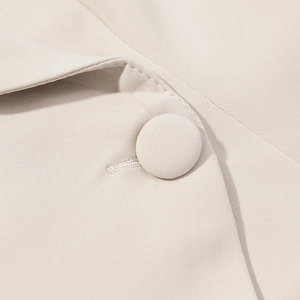 Macro view of a beige fabric-covered button on a high-quality twill blazer set