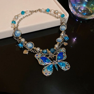 Détail macro du collier pendentif papillon argenté avec cristaux bleus et perles rondes