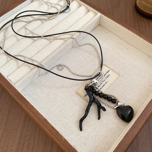 Detail of vintage double-layer necklace with black branch pendant and heart charm