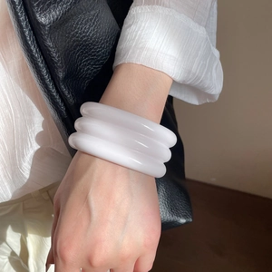 Close-up of three-layered white resin bangles with smooth finish on a female wrist
