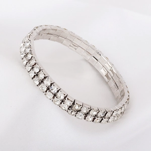 Detail of double-row rhinestone tennis bracelet on white silk with shiny silver finish