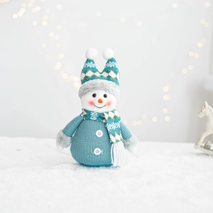 Close-up of knitted teal and white snowman doll with soft holiday bokeh background