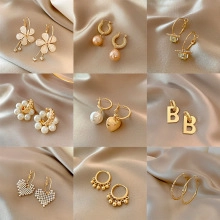 Detailed grid of nine golden earring styles with pearls and crystals on silk fabric