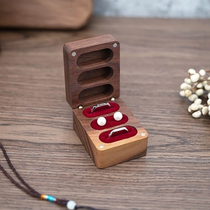 Black walnut wood ring box with red velvet lining holding silver rings and pearl earrings