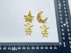 Detail macro view of hammered 18K gold plated star moon earrings with scale ruler