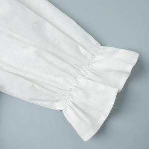 Detail view of elastic ruffled cuffs on a white linen shirt with textured fabric finish