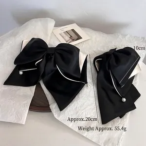 Elegant black and white contrast bow hair clip with pearl pendant on fabric ribbon