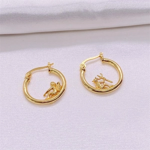 Macro view of gold plated asymmetric angel and devil earrings on white silk fabric