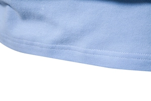 Vue macro de l'ourlet du polo bleu clair montrant la maille piquée et les coutures