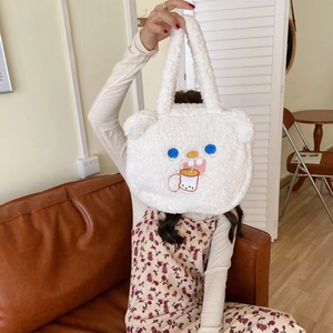 Detail of cute white fleece handbag with cartoon embroidery held by a model in a cozy room
