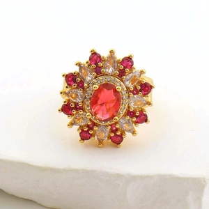 Close-up of golden ring with oval red gemstone and floral crystal halo on stone base