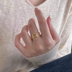 Detail of three intertwined golden rings worn on index finger for a minimalist look