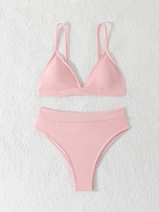 Pink ribbed bikini set with halter triangle top and high waist bottom on plush background