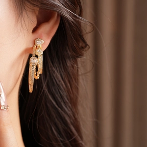Close-up of gold three-layer oval drop earrings with sparkling pavé cubic zirconia diamonds
