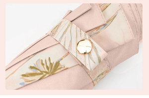 Detail of pink floral umbrella fabric with golden metallic button and fabric texture
