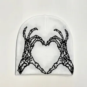 Detailed view of white knitted beanie featuring black skeleton hands heart jacquard pattern
