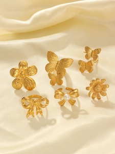 Detailed set of 18k gold butterfly and flower rings on silk background fabric