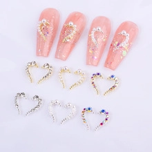 Macro shot of heart-shaped nail charms with rhinestones and pearls in gold and silver