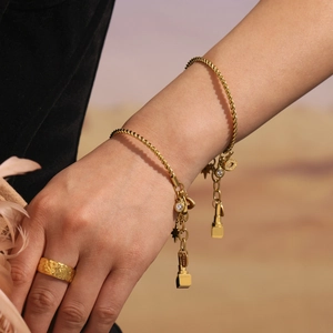 Goldenes Kordelarmband mit Zirkonia-Anhängern und Ring an Model in Wüstenlandschaft