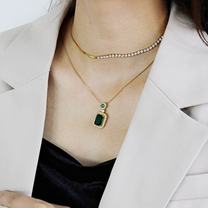 Elegant gold necklace set with rectangular green emerald pendant and tennis chain detail