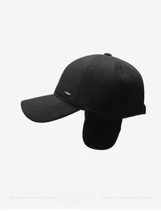 Detail view of winter baseball cap with earflaps, black wool fabric and metal logo
