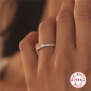 Detail of 925 sterling silver ring with central round diamond and pave accents on hand