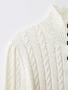 Detail of white cable-knit sweater featuring a high collar and decorative black buttons