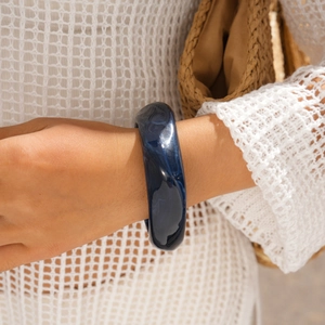 Detail of chunky resin bangle with blue marble pattern worn with white knit top