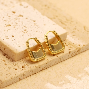 Macro detail of golden handbag earrings featuring horizontal wavy textures and smooth finish