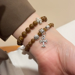 Gros plan de bracelets en perles marron avec breloques croix argentées sur un poignet