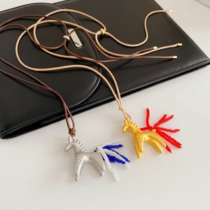 Détail de pendentifs chevaux avec crinières en perles sur colliers en cordon ciré